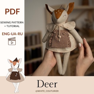 May include: A handmade deer doll with a brown and white spotted head, wearing a beige dress with a brown checkered apron. The doll has long, slender legs and is held up by hands. Text on the image says "Deer" and "PDF Sewing Pattern + Tutorial".