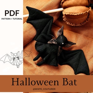 Könnte beinhalten: Eine schwarze Filz-Halloween-Fledermaus mit einer braunen Filz-Schleife. Die Fledermaus liegt auf einem braunen Stoffhintergrund. Das Bild enthält den Text "Halloween Bat" und "@WHITE_COUTURIER".