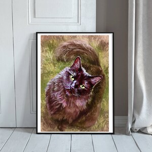 May include: A framed art print of a black cat with green eyes, looking upwards. The cat has fluffy fur and is set against a background of green and brown tones, resembling grass. The artwork is displayed on a white wall.