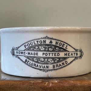 Peut inclure: Pot en céramique blanche avec une étiquette noire et blanche qui indique "Poulton & Noel Home-Made Potted Meats Belgravian Brand".