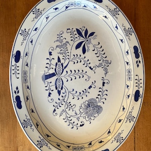 May include: A white oval serving platter with a blue floral design. The design features a stylized tree with leaves and flowers.