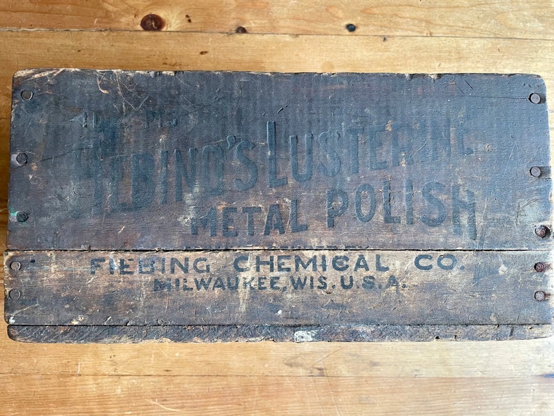 May include: A vintage wooden box with black lettering that reads "Fiebing's Lusterine Metal Polish" and "Fiebing Chemical Co. Milwaukee, Wis. U.S.A."
