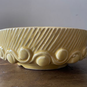 May include: A yellow ceramic planter with a wavy, textured rim and a striped pattern on the sides.