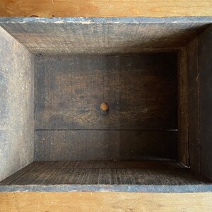 May include: A wooden box with a dark brown stain. The box is empty and has a small hole in the bottom.