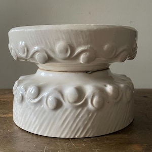 May include: Two white ceramic bowls with a decorative swirl pattern around the rim. The bowls are stacked on top of each other.