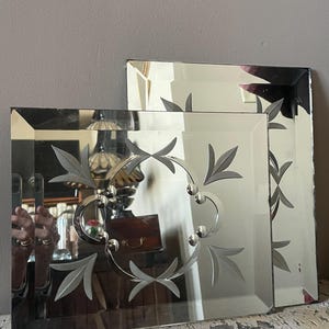 以下が含まれることがあります： エッチングされた花の模様が施された2つの長方形の鏡。鏡は透明で、面取りされたエッジがあります。大きな鏡は中央に花のモチーフがあり、小さな鏡はよりシンプルなデザインです。白く塗装された、使い古された表面に表示されています。