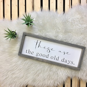 May include: A grey wooden sign with white lettering that reads "These are the good old days."