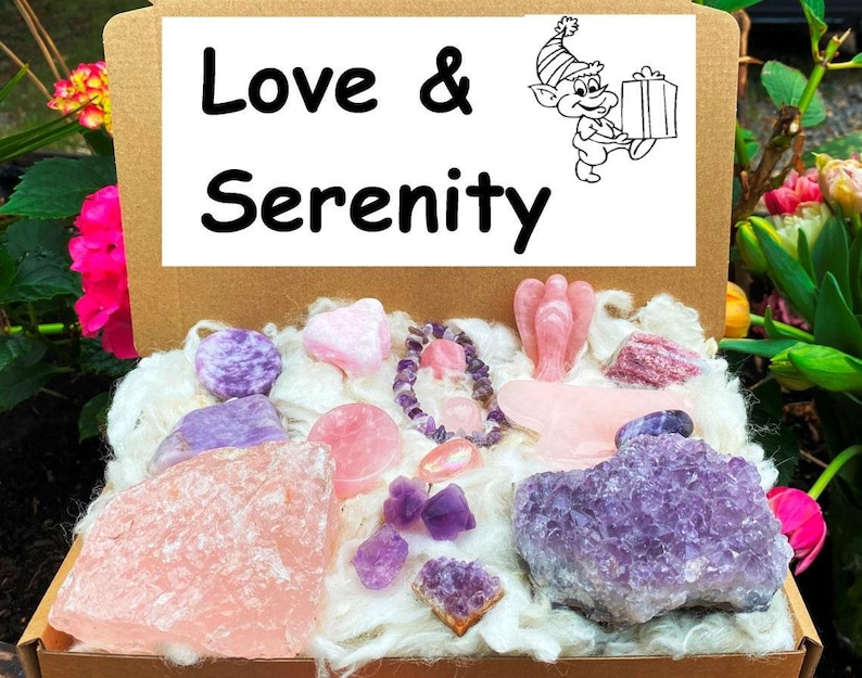 May include: A box filled with pink and purple crystals, including amethyst, rose quartz, and selenite. The box is labeled "Love & Serenity".