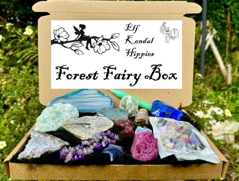 May include: A cardboard box filled with various crystals and stones. The box is labeled "Forest Fairy Box" and has a logo with a fairy and the text "Elf Kendal Hippies".