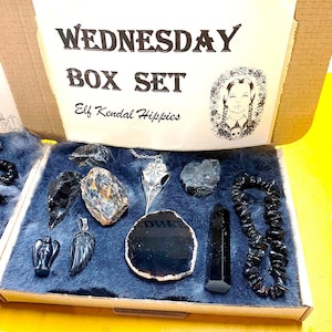 May include: A box set with the text "WEDNESDAY BOX SET Elf Kendal Hippies" on the lid. The box contains a variety of black crystals, a silver pendant, and a black beaded bracelet.