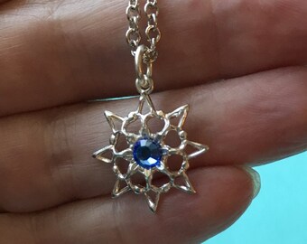Op de afbeelding: Een zilveren ketting met een blauwe kristallen sneeuwvlok hanger.