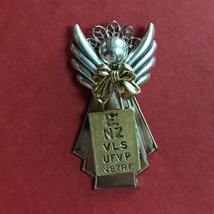 May include: Silver angel ornament with gold bow and eye chart. The eye chart reads: E, NZ, VLS, UFVP, NSTRF.