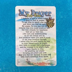 May include: A prayer card with the text "My Prayer For You" in a decorative font. The card features a gold-colored angel pin and a poem about faith and well-being. The background is a light blue.