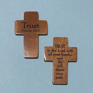 May include: Two wooden crosses with engraved text. One cross reads "Trust Proverbs 3:5-0." The other cross reads "TRUST in the Lord, with all your heart... and He will direct your path." The crosses are brown and have a light blue background.
