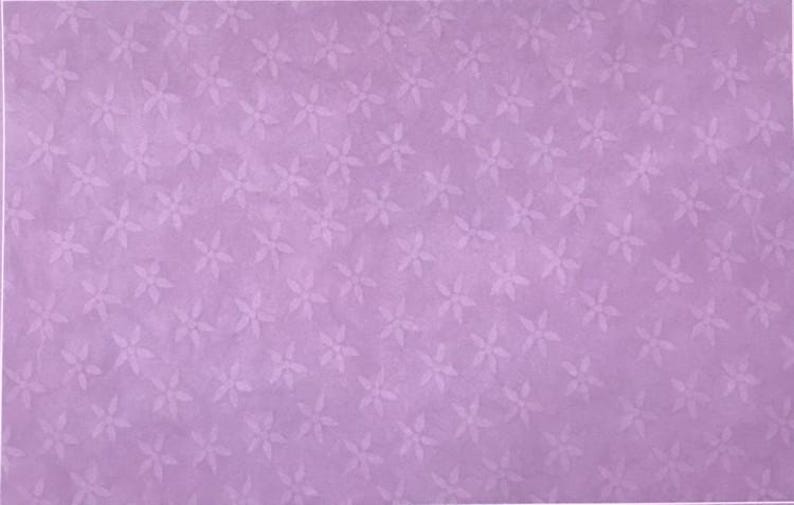 Puede incluir: Un fondo de color morado claro con un patr&oacute;n repetitivo de peque&ntilde;as flores de cinco p&eacute;talos en un tono morado ligeramente m&aacute;s claro. La superficie tiene una textura sutil y uniforme en todas partes, creando un aspecto visual suave y constante.