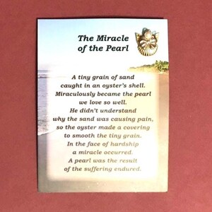 May include: A card with the title "The Miracle of the Pearl" and a poem about a pearl's creation. The card features a beach scene and a small illustration of a shell with a pearl.