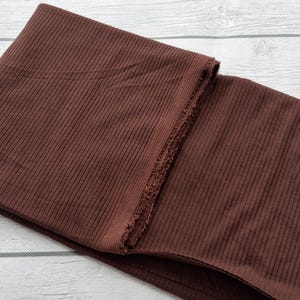 May include: A brown ribbed fabric folded in half. The fabric has a subtle sheen and a soft texture.