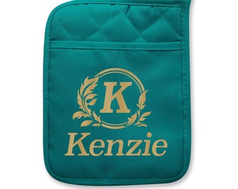 May include: Teal quilted oven mitt with a gold monogram of the letter "K" surrounded by leaves and the name "Kenzie" below.