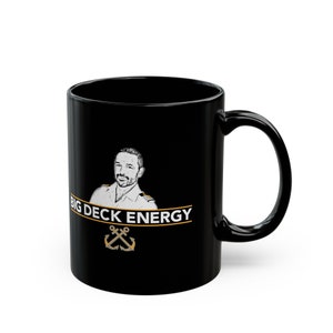 May include: Black ceramic coffee mug with a white image of a man with a white shirt and a gold tie. The text "BIG DECK ENERGY" is printed in white on a gold banner. Two gold anchors are below the text.
