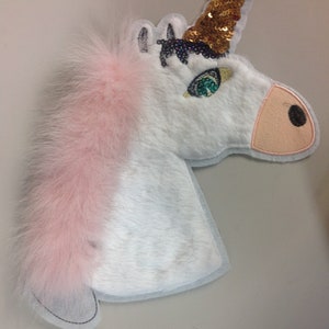 May include: White unicorn head applique with a pink fur mane, gold sequin horn, and green eye detail.
