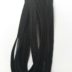 May include: A close-up of a bundle of black elastic cord. The cord is tightly wound and appears to be made of a soft, stretchy material.