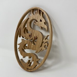 May include: A wooden wall hanging in the shape of a circle with a detailed carving of a dragon inside.