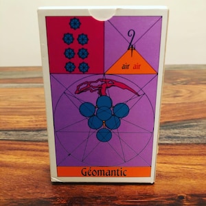 May include: A white box with a purple, orange, and red geometric design. The box has the text "Géomantic" on the bottom and "air air" in the upper right corner.