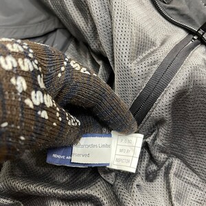 Puede incluir: Primer plano de una etiqueta negra con texto blanco que dice "Motorcycles Limited Reserved" y una etiqueta blanca con texto negro que dice "P.O. NO. MFD BY INSPECTOR".