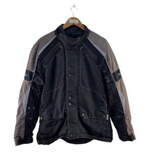Puede incluir: Chaqueta de moto negra y gris con cierre de cremallera y m&uacute;ltiples bolsillos. La chaqueta tiene un dise&ntilde;o de bloques de color gris y negro.