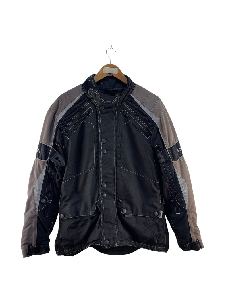Puede incluir: Chaqueta de moto negra y gris con cierre de cremallera y m&uacute;ltiples bolsillos. La chaqueta tiene un dise&ntilde;o de bloques de color gris y negro.