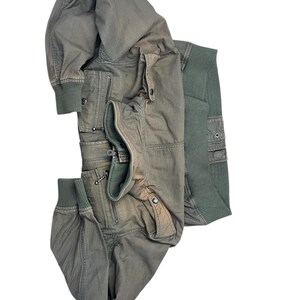 May include: An olive green bomber jacket with multiple pockets and a ribbed knit collar and cuffs. The jacket has a zipper closure and a relaxed fit. The jacket is made of a durable material and is suitable for cooler weather.