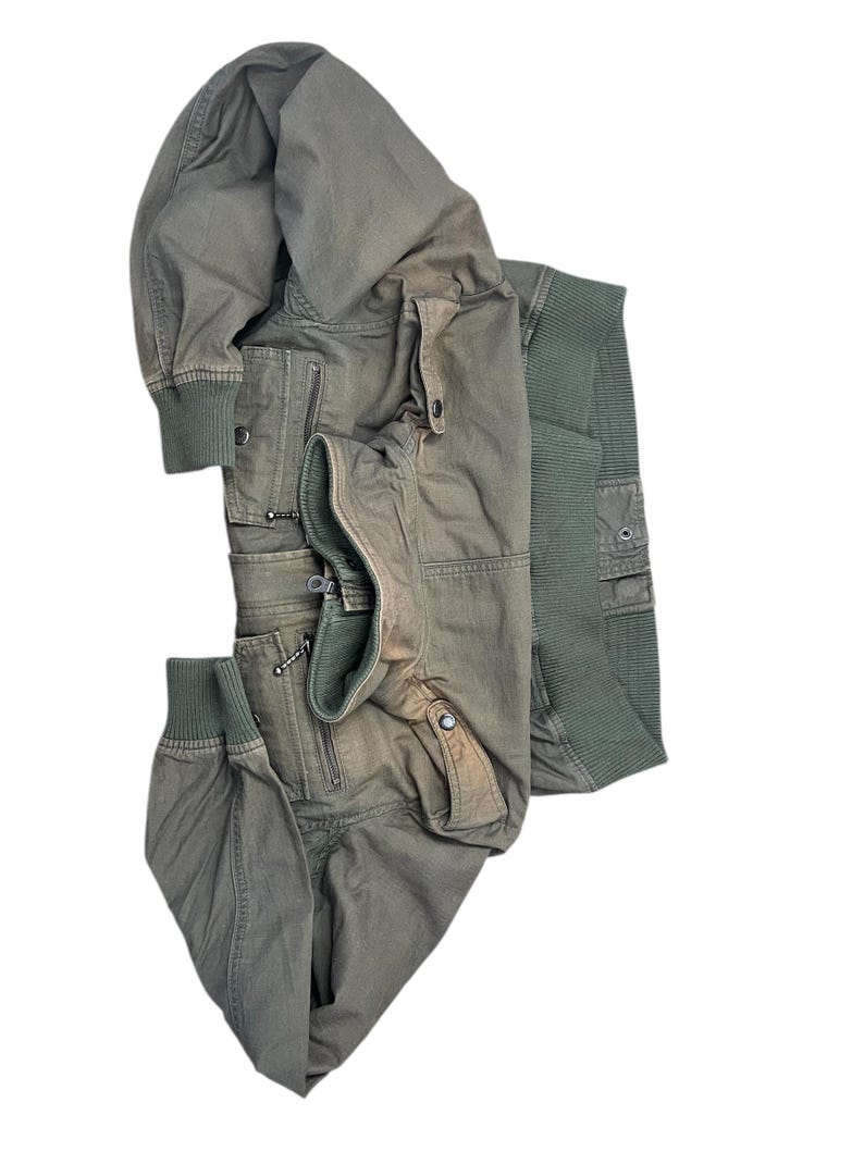 May include: An olive green bomber jacket with multiple pockets and a ribbed knit collar and cuffs. The jacket has a zipper closure and a relaxed fit. The jacket is made of a durable material and is suitable for cooler weather.