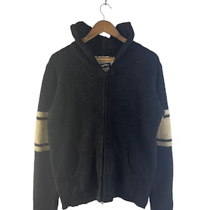May include: Black zip-up hooded sweater with tan stripes on the sleeves. The sweater has a textured, fuzzy appearance, a hood, and two front pockets. The sweater is hanging on a wooden hanger.