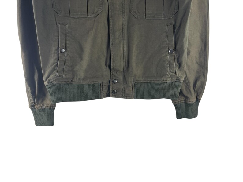 May include: Olive green bomber jacket with ribbed cuffs and hem. Features two front pockets with button closures and two chest pockets. The jacket has a button-up front and a classic bomber style.