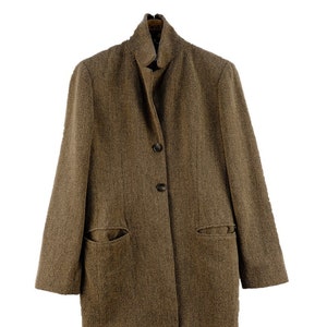 Peut inclure: Un blazer en tweed marron avec un col montant, une fermeture à deux boutons et deux poches à rabat.
