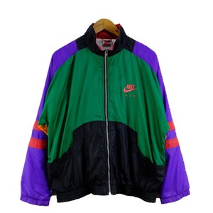 Puede incluir: Una chaqueta vintage Nike Air con un dise&ntilde;o de bloques de color verde, negro, morado y rojo. La chaqueta tiene una cremallera y un cuello alto. El logotipo de Nike Air est&aacute; impreso en la parte delantera de la chaqueta en rojo y blanco.