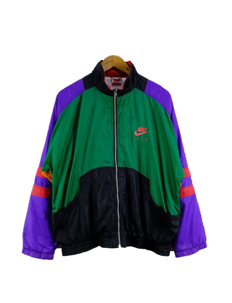 Puede incluir: Una chaqueta vintage Nike Air con un dise&ntilde;o de bloques de color verde, negro, morado y rojo. La chaqueta tiene una cremallera y un cuello alto. El logotipo de Nike Air est&aacute; impreso en la parte delantera de la chaqueta en rojo y blanco.