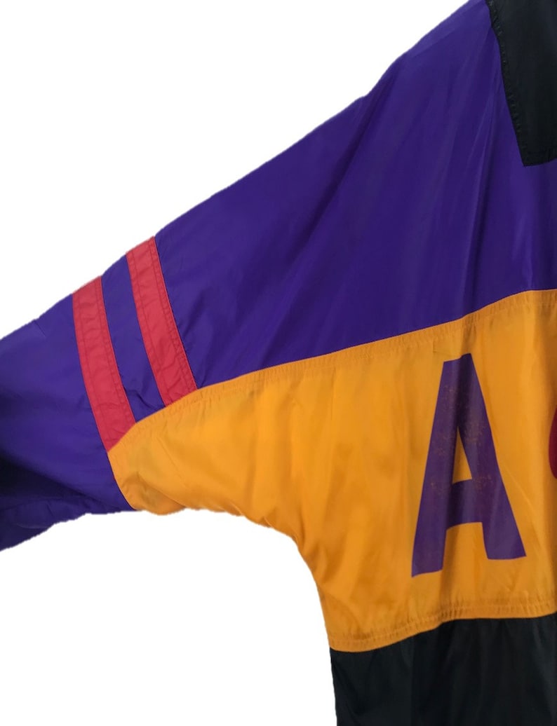 Puede incluir: Una chaqueta de color bloque en morado, rojo, amarillo y negro con una gran letra "A" morada en la secci&oacute;n amarilla.