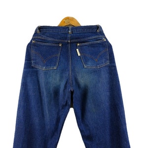 以下が含まれることがあります： 5つのポケットが付いたクラシックなスタイルの青いデニムジーンズ。ジーンズはハイウエストでストレートレッグです。