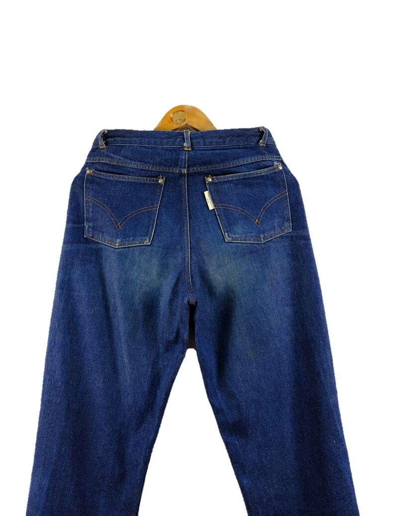 以下が含まれることがあります： 5つのポケットが付いたクラシックなスタイルの青いデニムジーンズ。ジーンズはハイウエストでストレートレッグです。