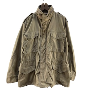 Puede incluir: Una chaqueta vintage de estilo militar de color verde oliva con cierre de botones y múltiples bolsillos.