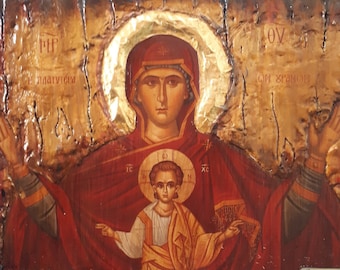 May include: A hand-painted icon of the Virgin Mary and baby Jesus. The icon is on a wooden panel with a gold background. The Virgin Mary is wearing a red robe and a blue cloak. She is holding baby Jesus in her arms. The icon is surrounded by a gold halo.
