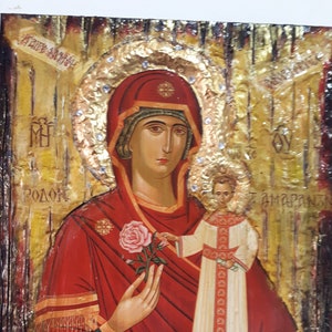 Könnte beinhalten: Ein religiöses Ikonenbild, das die Jungfrau Maria zeigt, die ein Jesuskind hält. Die Jungfrau Maria trägt eine rote Robe mit goldenen Verzierungen und eine Krone. Das Jesuskind trägt eine weiße Robe mit goldenen Verzierungen. Der Hintergrund ist golden mit einem Heiligenschein um den Kopf der Jungfrau Maria.