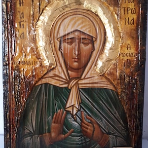 May include: A hand-painted icon of the Virgin Mary, with a gold background and a wooden frame. The icon depicts Mary with her hands clasped in prayer, and the text "Ma Tro Na H Rosiada" is written in Greek on the right side of the icon.