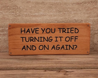 May include: A wooden sign with the text "Have you tried turning it off and on again?" in black lettering.
