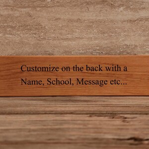 May include: A wooden sign with the text "Customize on the back with a Name, School, Message etc..." engraved on it.