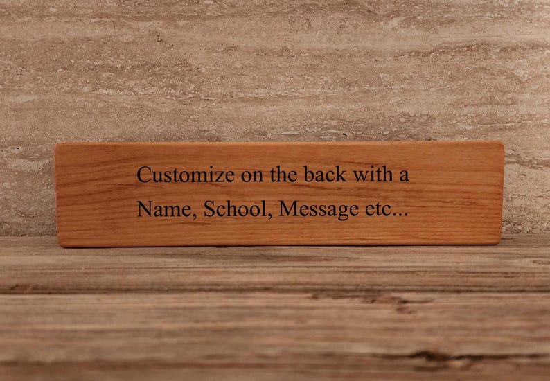 May include: A wooden sign with the text "Customize on the back with a Name, School, Message etc..." engraved on it.