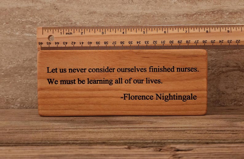 May include: A wooden plaque with a quote from Florence Nightingale that reads: "Let us never consider ourselves finished nurses. We must be learning all of our lives."