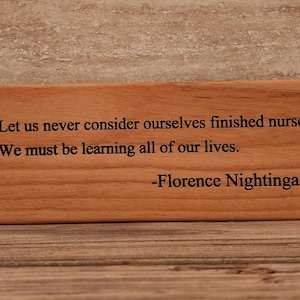 May include: Wooden plaque with a quote by Florence Nightingale: "Let us never consider ourselves finished nurses. We must be learning all of our lives."