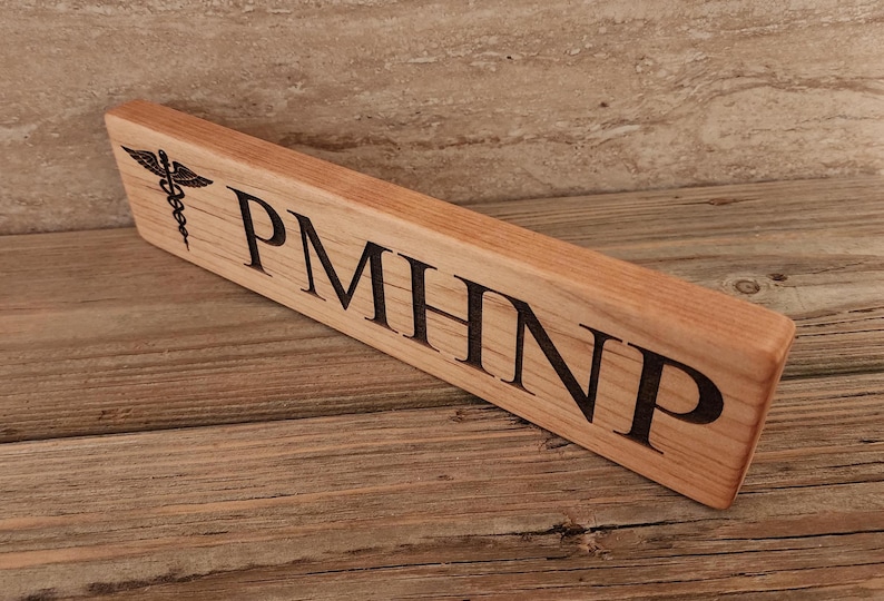 May include: A wooden sign with the text "PMHNP" and a medical symbol engraved on it.